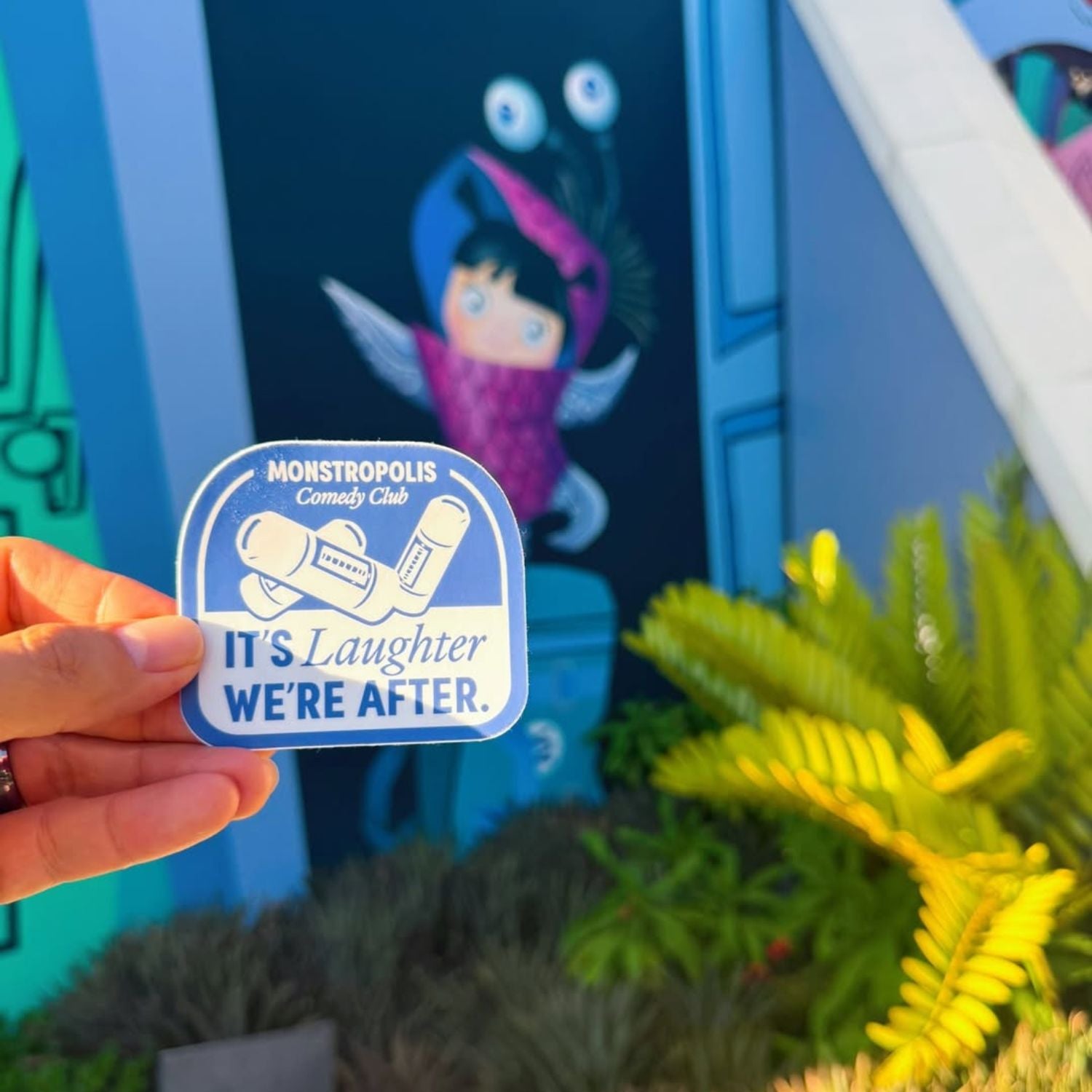Monstropolis Comedy Club Disney-inspired sticker with phrase ‘It’s Laughter We’re After’ and three laugh canisters.
