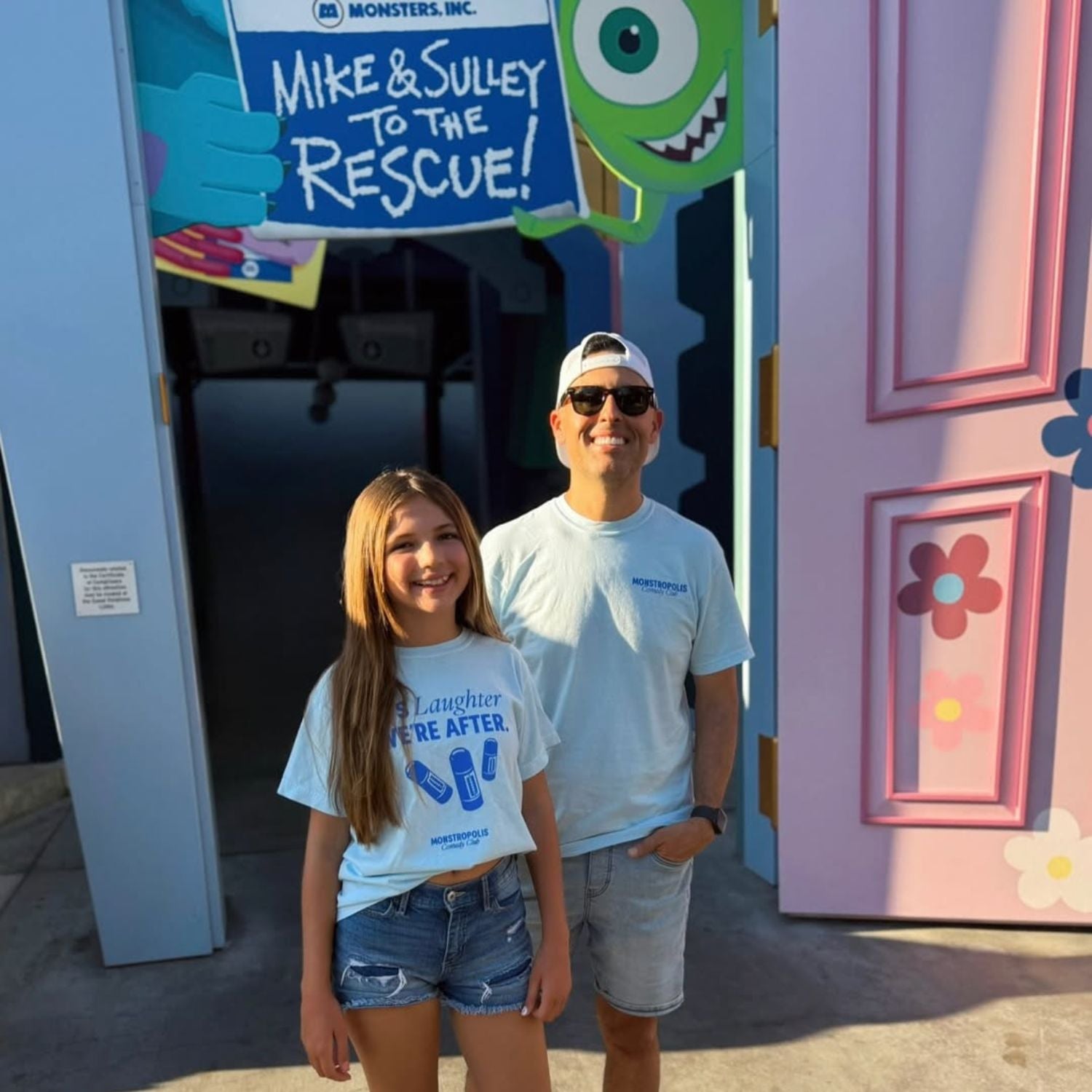 Front view of kids’ Disney-inspired Monstropolis Comedy Club t-shirt featuring the phrase ‘It’s Laughter We’re After’ above three laugh canisters with Monstropolis Comedy Club text underneath.