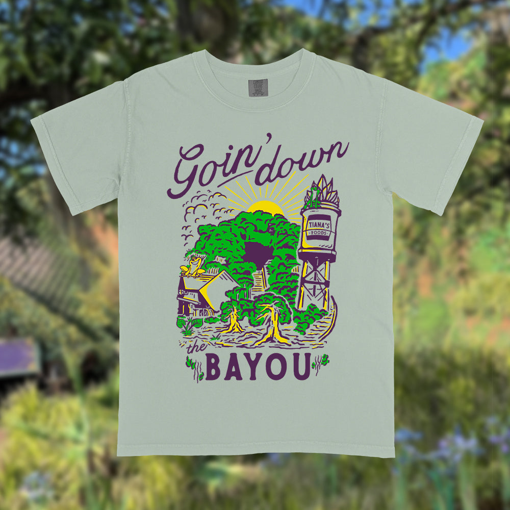Front view of Disney-inspired Goin’ Down the Bayou t-shirt featuring text ‘Goin’ Down the Bayou’ above artwork of Tiana’s Bayou Adventure ride exterior with the big drop, Tiana’s Foods water tower, and cypress trees.
