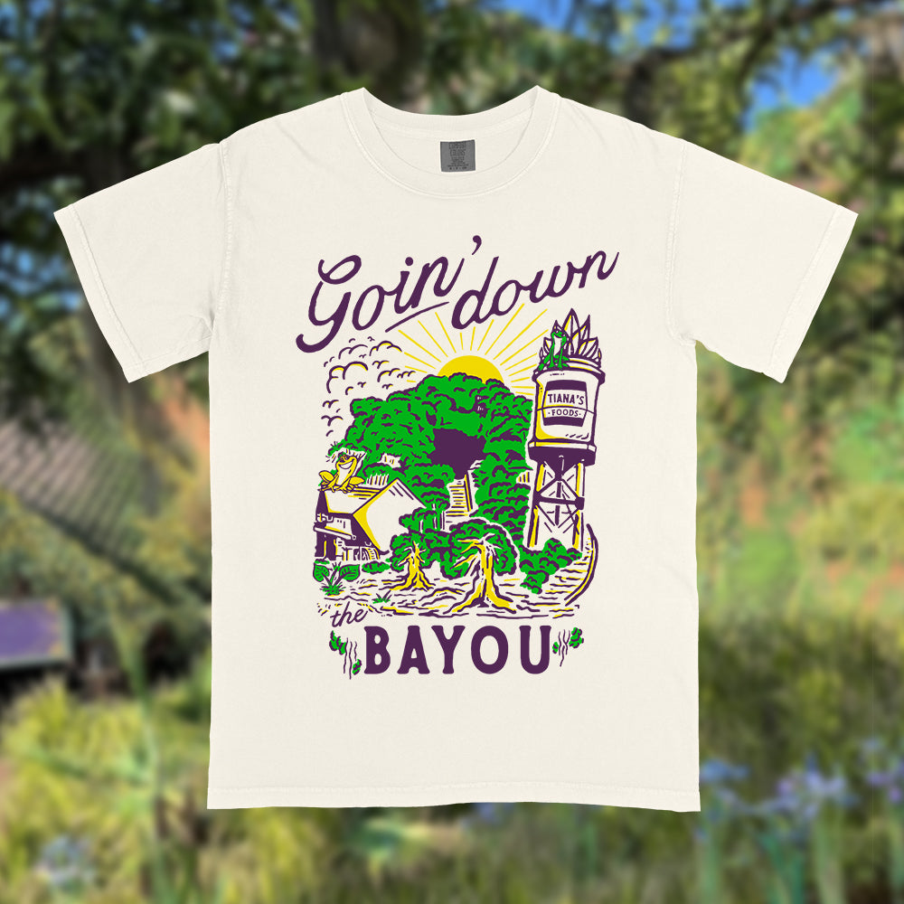 Front view of Disney-inspired Goin’ Down the Bayou t-shirt featuring text ‘Goin’ Down the Bayou’ above artwork of Tiana’s Bayou Adventure ride exterior with the big drop, Tiana’s Foods water tower, and cypress trees.