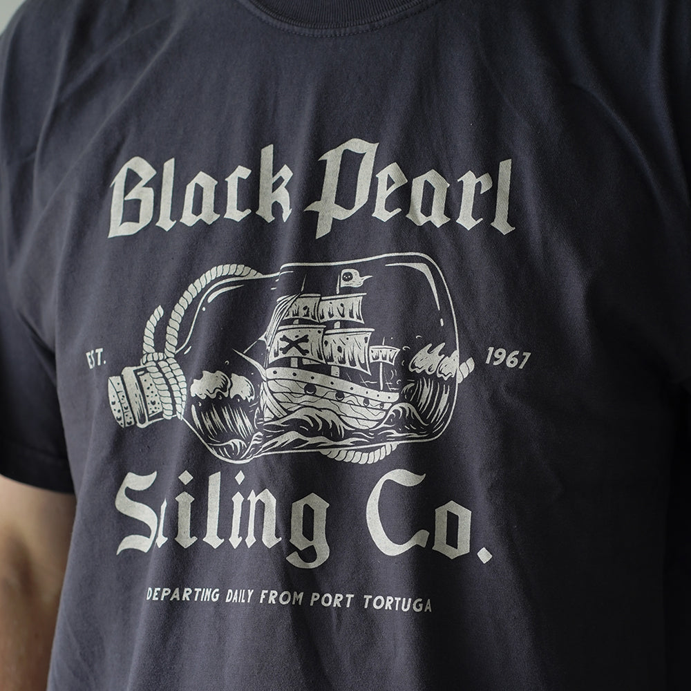 Front view of Disney-inspired Black Pearl Sailing Co. t-shirt featuring a ship-in-a-bottle design with the Black Pearl, small text ‘Est. 1967,’ and the phrase ‘Departing Daily From Port Tortuga.