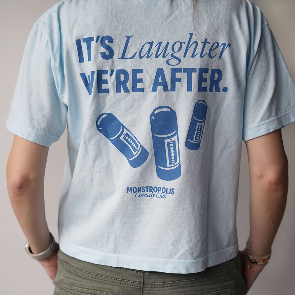 Back view of Disney-inspired Monstropolis Comedy Club crop top with the phrase ‘It’s Laughter We’re After’ above three laugh canisters and Monstropolis Comedy Club text underneath.