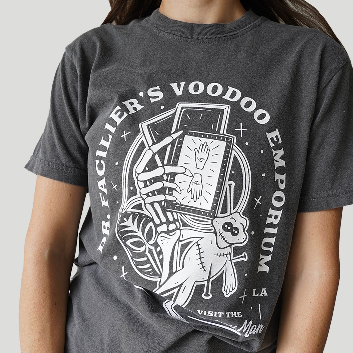 Front view of Disney-inspired Dr. Facilier’s Voodoo Emporium t-shirt with text ‘Dr. Facilier’s Voodoo Emporium,’ ‘NOLA,’ and ‘Visit the Shadow Man,’ featuring a voodoo frog and a skeleton hand holding playing cards.