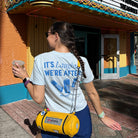 Woman at a Disney park holding a latte and wearing the Monstropolis Comedy Club t-shirt with ‘It’s Laughter We’re After’ and three laugh canisters on the back.